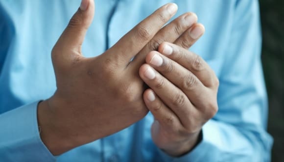 Close-up of a man gently holding his hand, symbolizing comfort or pain relief.