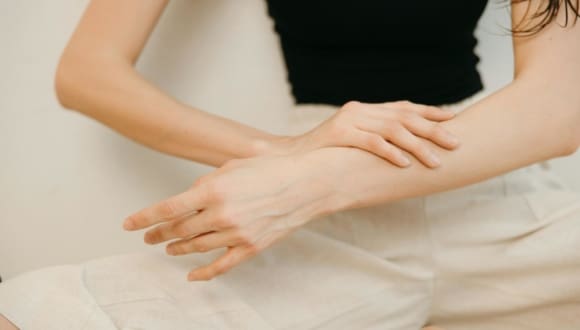 Close-up of a woman applying cosmetic cream on her arm for skincare.